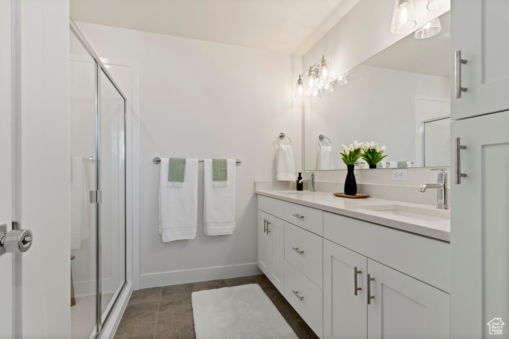 Full bathroom featuring double vanity, a stall shower, baseboards, and tile patterned floors