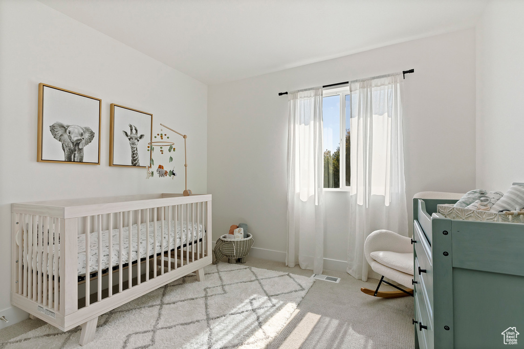 Carpeted bedroom with a nursery area and baseboards