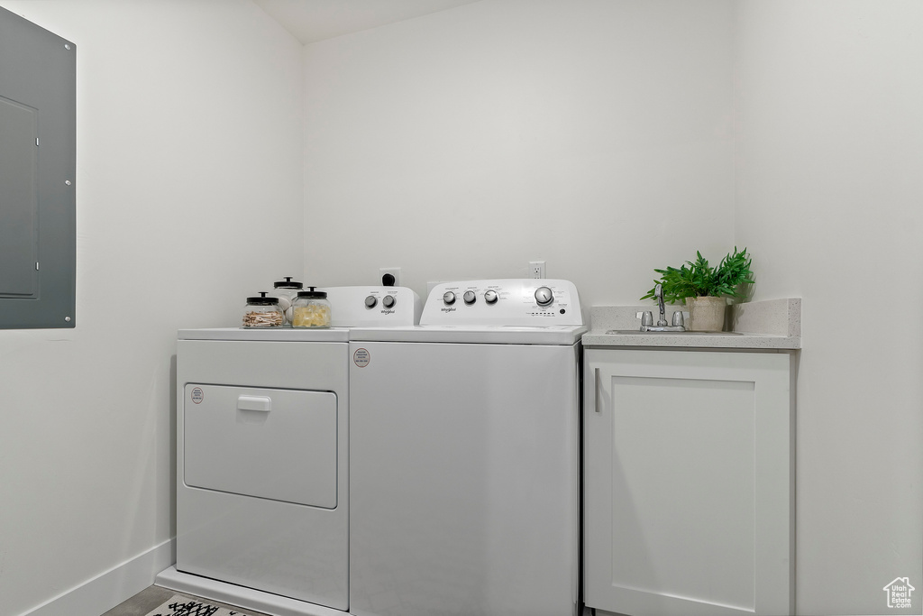 Laundry area featuring washing machine and clothes dryer, electric panel, baseboards, and cabinet space
