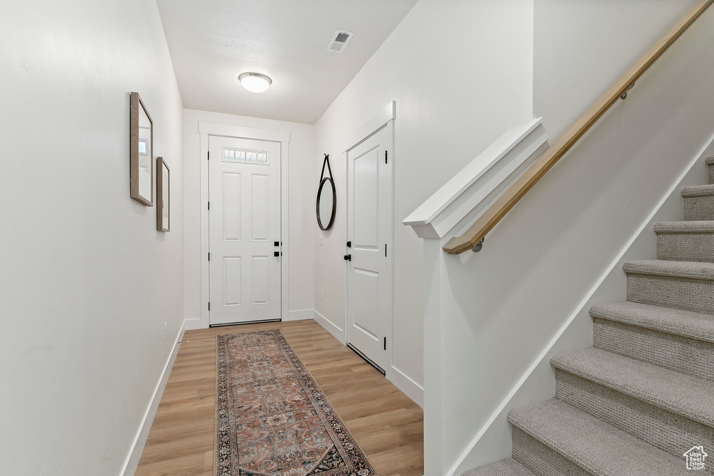 Entryway featuring stairway, light wood finished floors, and baseboards