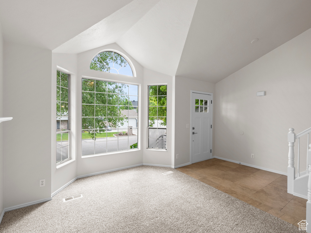 Foyer entrance featuring lofted ceiling, carpet, and baseboards