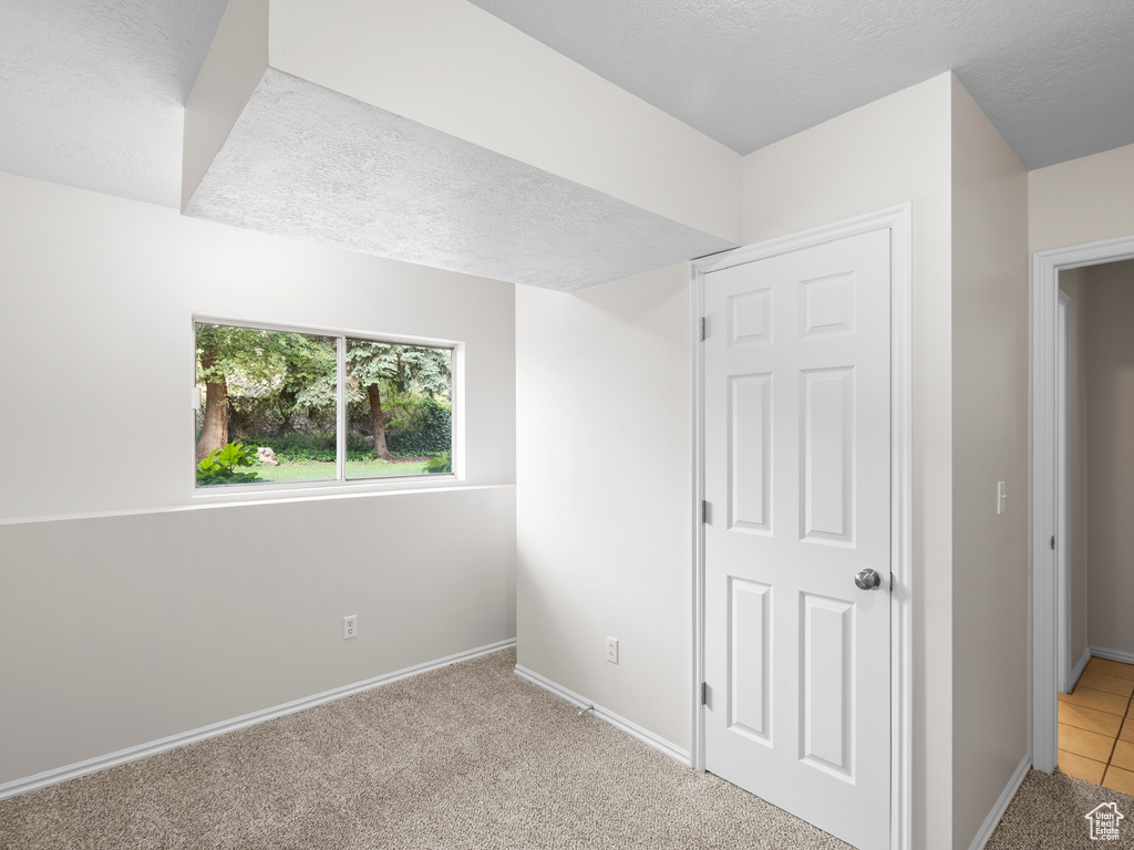 Unfurnished bedroom with a textured ceiling, baseboards, and light carpet