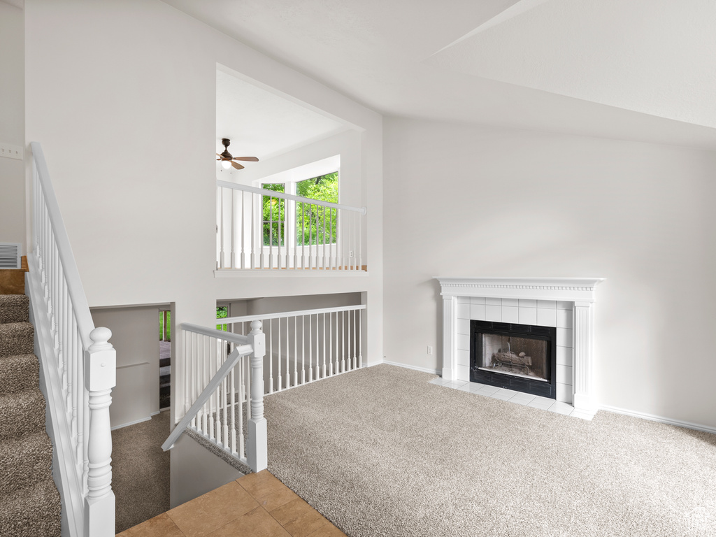 Unfurnished living room with carpet floors, lofted ceiling, a fireplace, ceiling fan, and baseboards