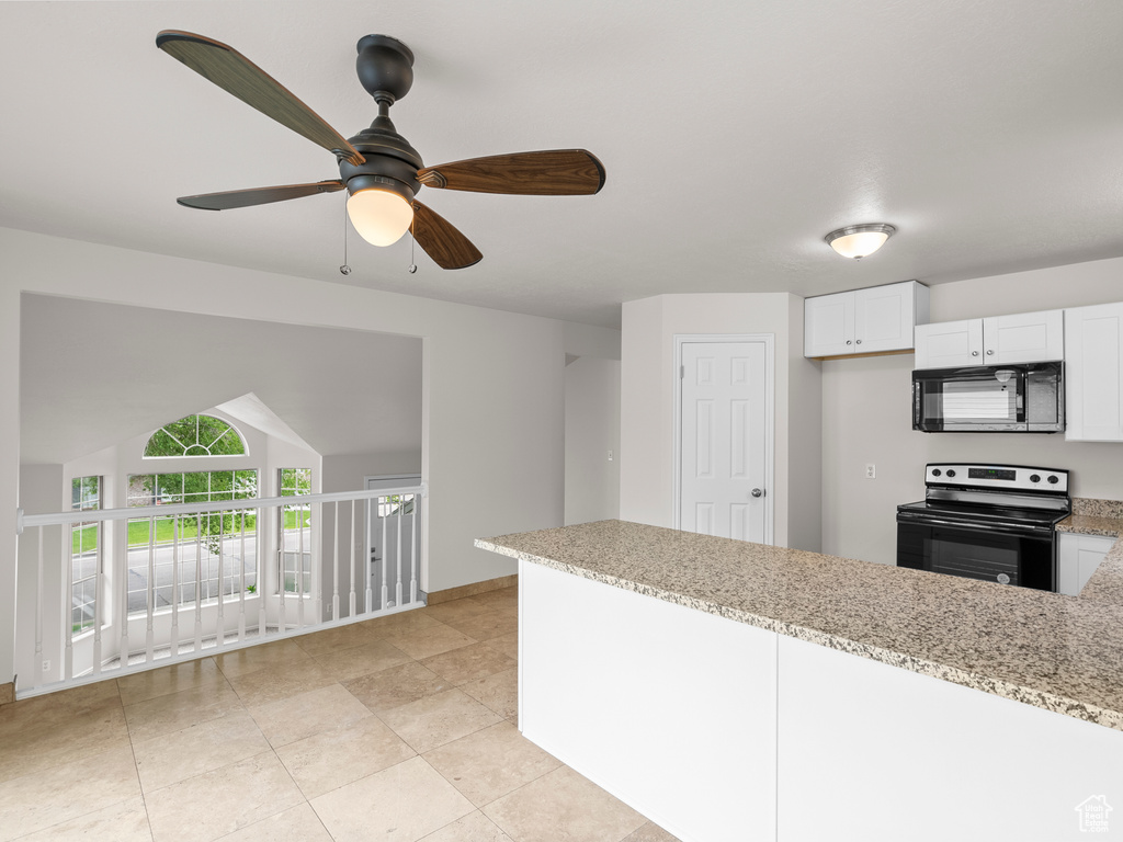 Kitchen featuring range with electric stovetop, black microwave, a peninsula, light stone countertops, and ceiling fan