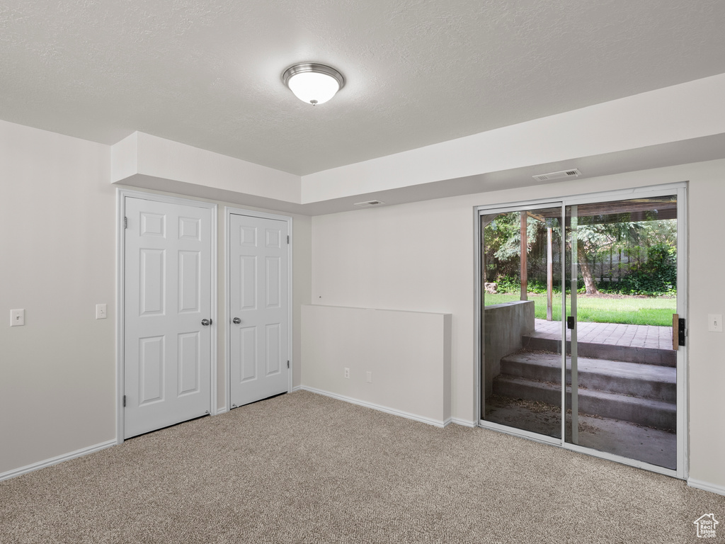 Unfurnished bedroom featuring access to exterior, carpet, baseboards, and a textured ceiling