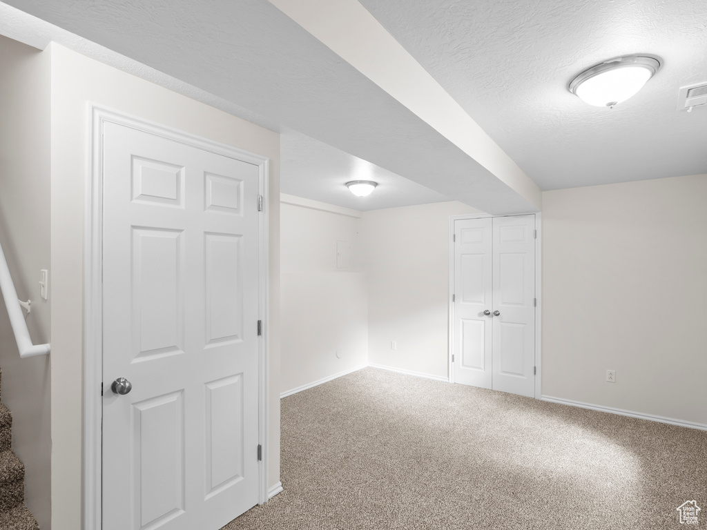 Basement featuring baseboards, carpet flooring, and a textured ceiling