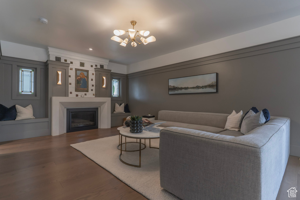 Living room featuring a chandelier, wood finished floors, a glass covered fireplace, and plenty of natural light