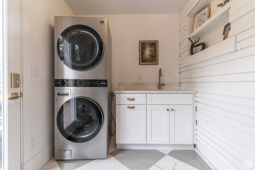 Clothes washing area with stacked washer and clothes dryer and cabinet space