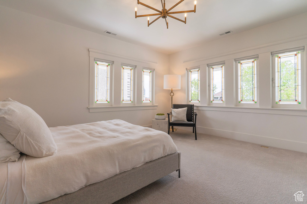 Carpeted bedroom featuring a chandelier and baseboards