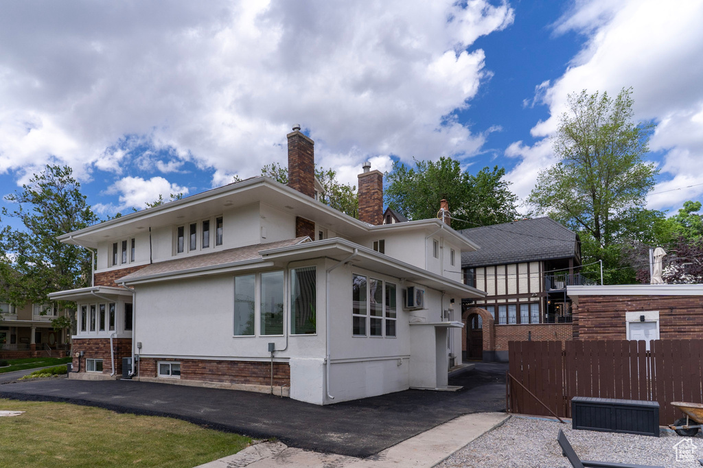 Rear view of property featuring stucco siding, fence, and a chimney