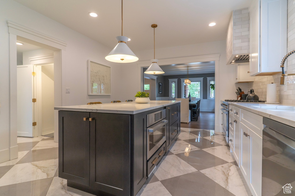 Kitchen with appliances with stainless steel finishes, white cabinets, backsplash, recessed lighting, and a sink