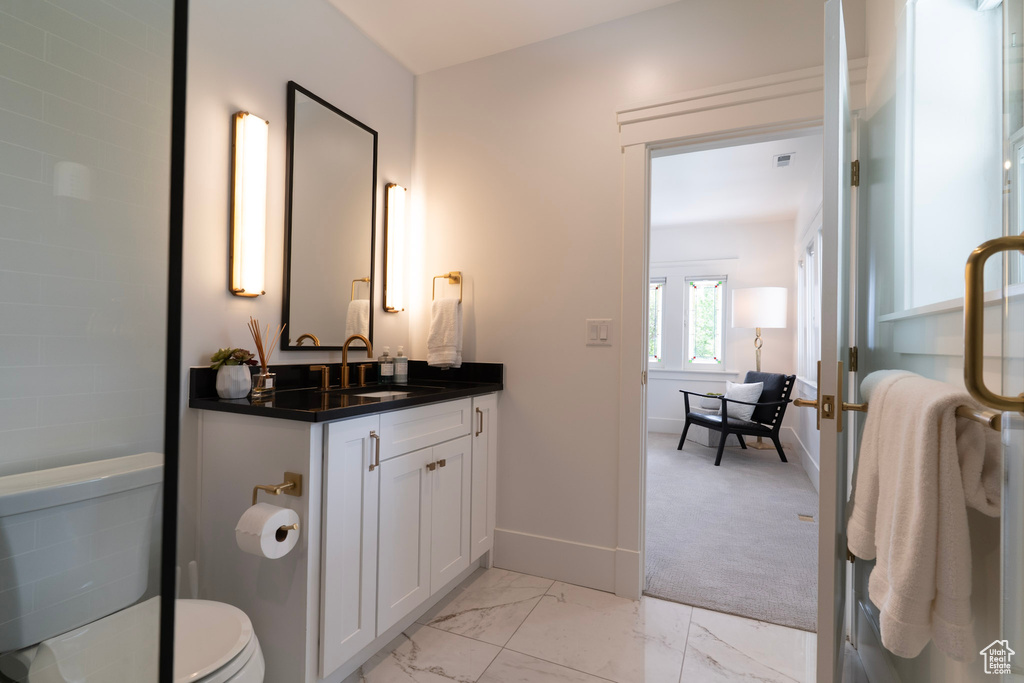 Bathroom featuring vanity, marble finish flooring, baseboards, and toilet