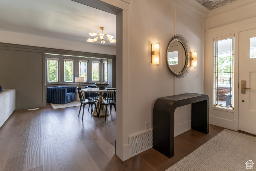Entrance foyer with wood finished floors, a chandelier, ornamental molding, and baseboards