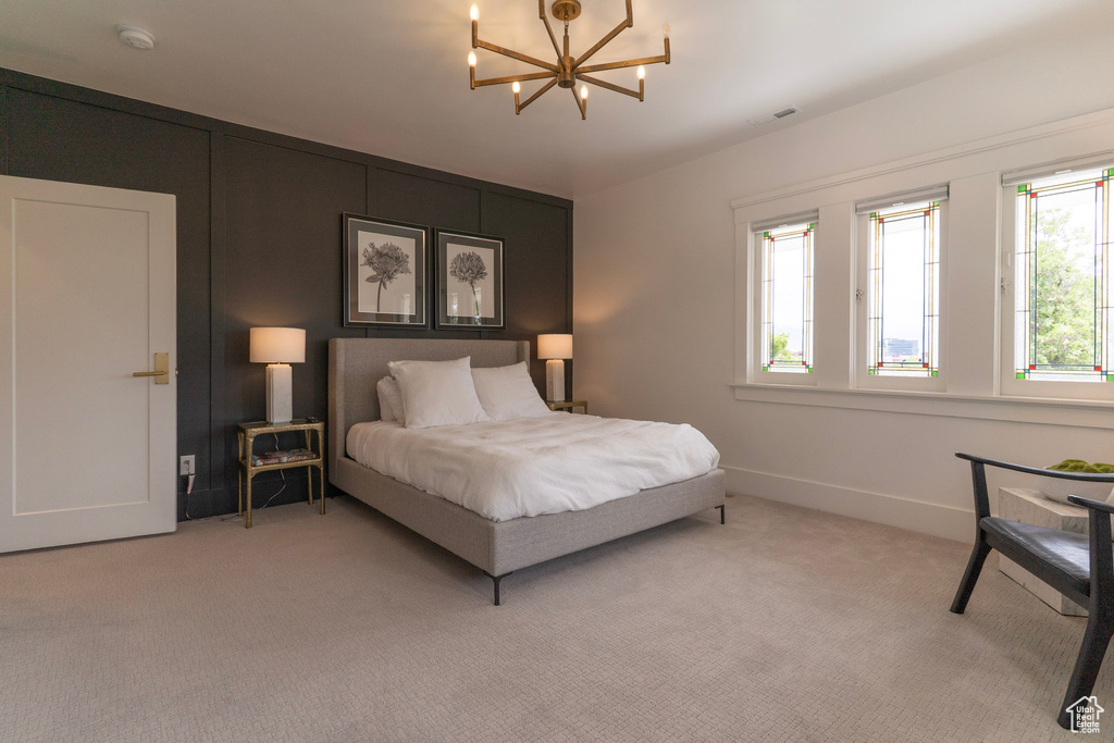 Bedroom with a chandelier, light colored carpet, and baseboards