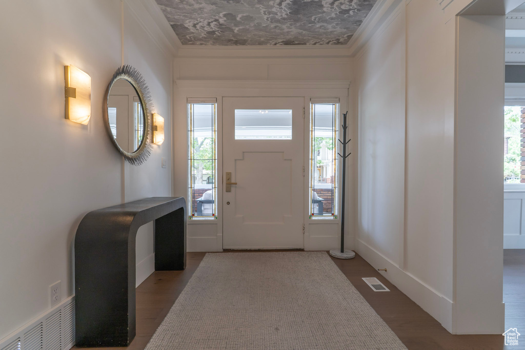 Foyer entrance with ornamental molding and wood finished floors