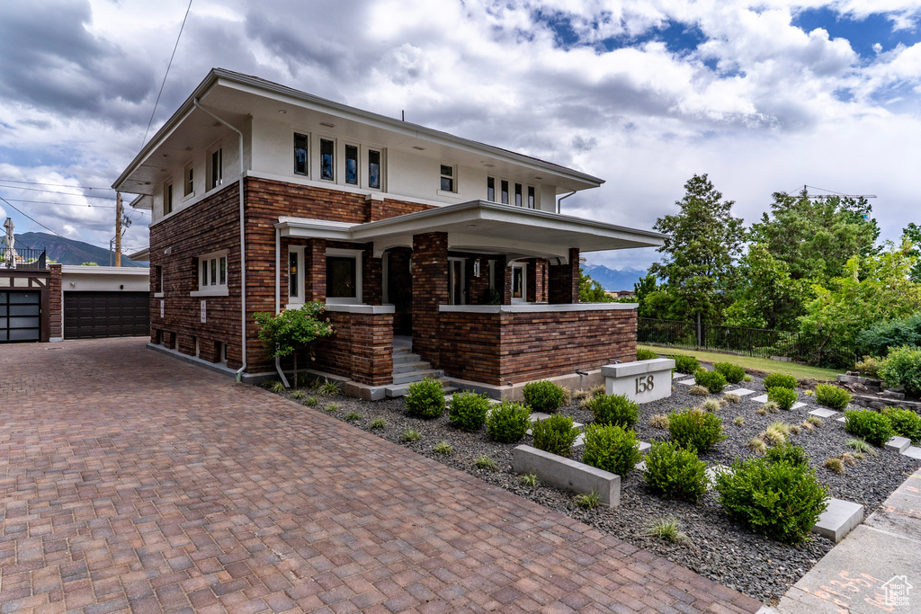 View of front of home featuring an outbuilding, fence, a garage, brick siding, and a porch