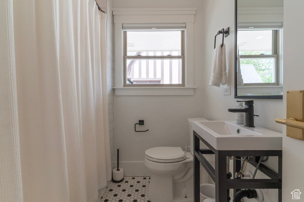 Bathroom with healthy amount of natural light, tile patterned floors, toilet, and vanity