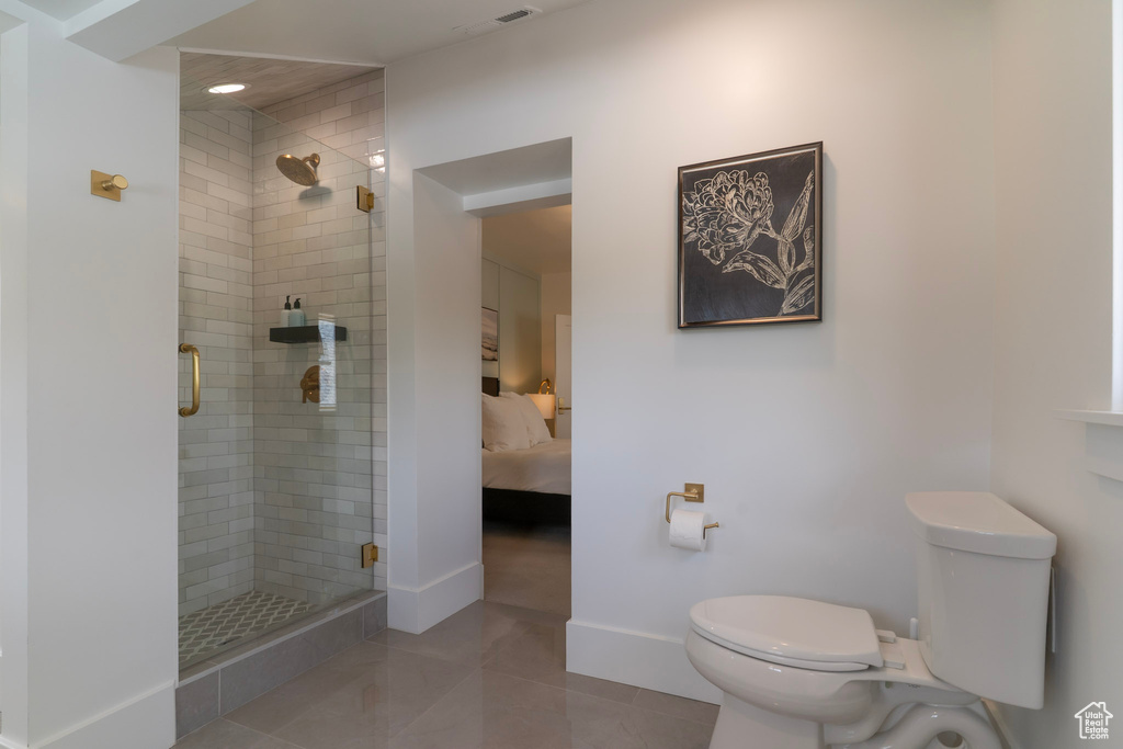 Bathroom featuring toilet, a stall shower, tile patterned floors, connected bathroom, and baseboards