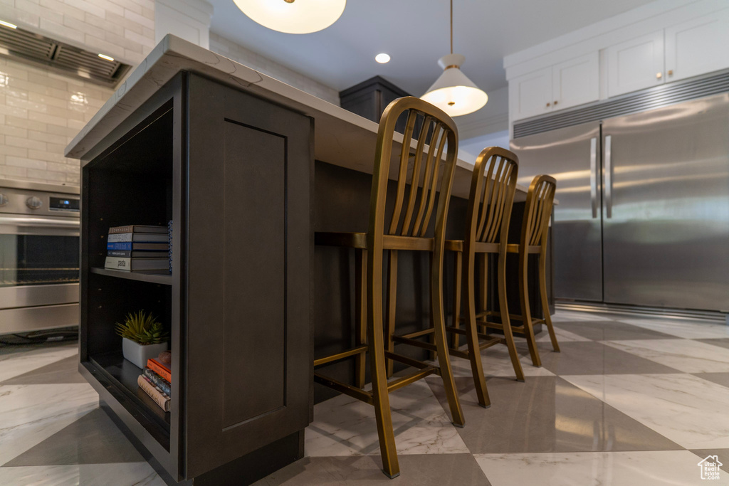 Kitchen featuring appliances with stainless steel finishes, white cabinetry, marble finish flooring, hanging light fixtures, and recessed lighting