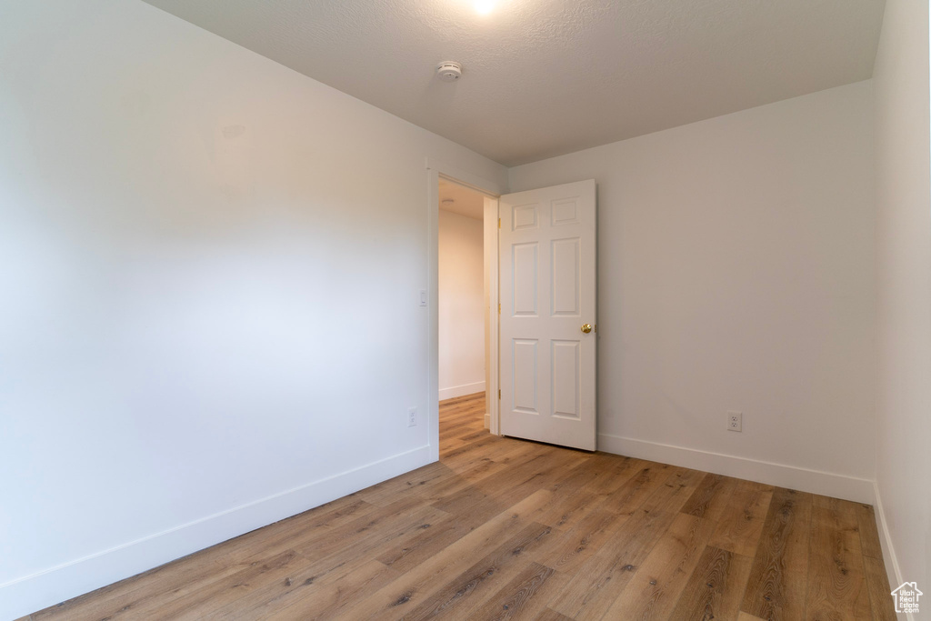 Unfurnished room featuring baseboards, a smoke detector, and light wood-style flooring
