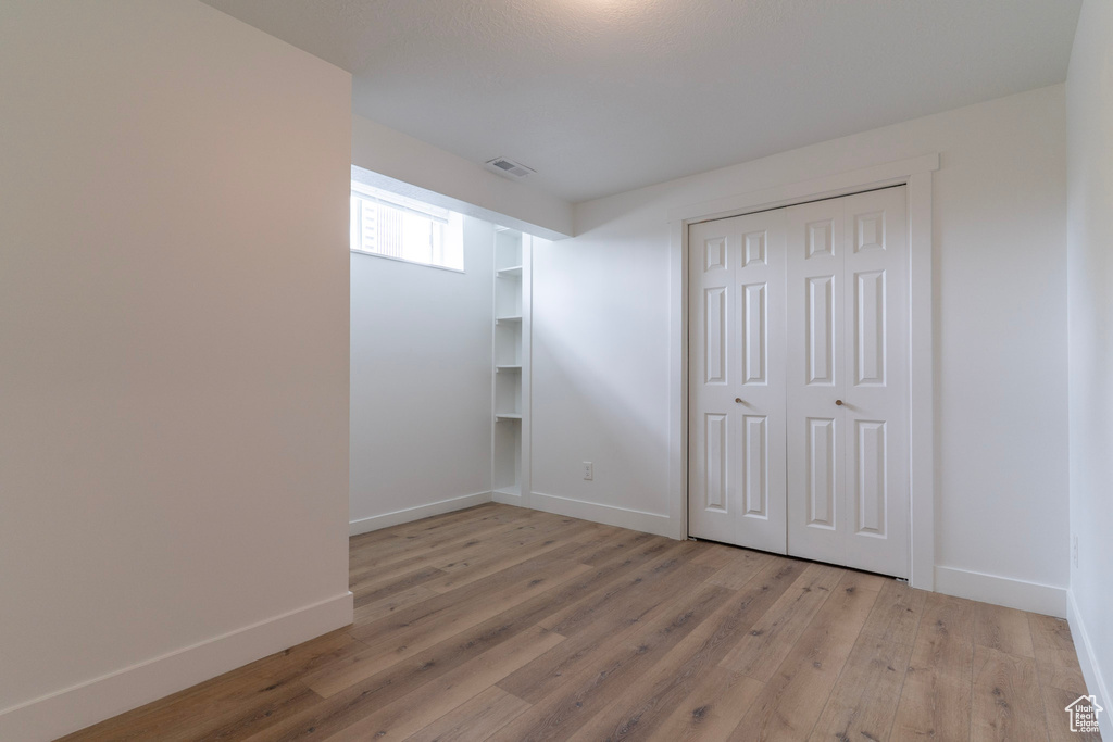 Unfurnished bedroom featuring light wood-type flooring, baseboards, and a closet