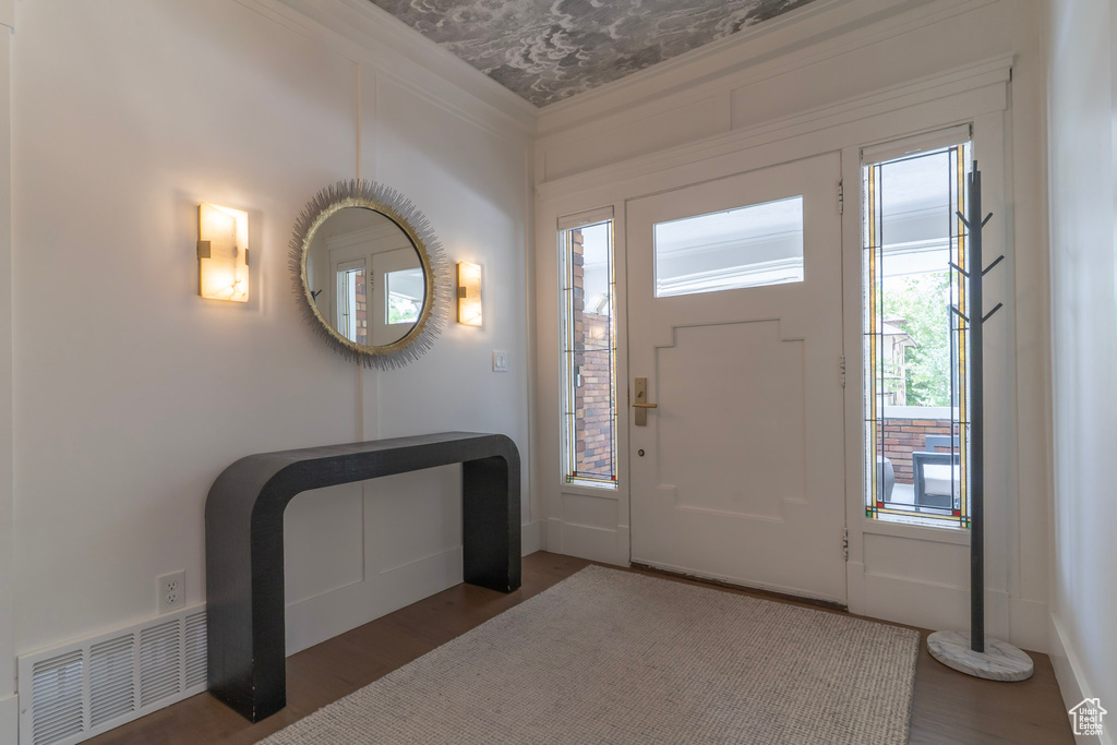 Foyer with wood finished floors, plenty of natural light, crown molding, and baseboards