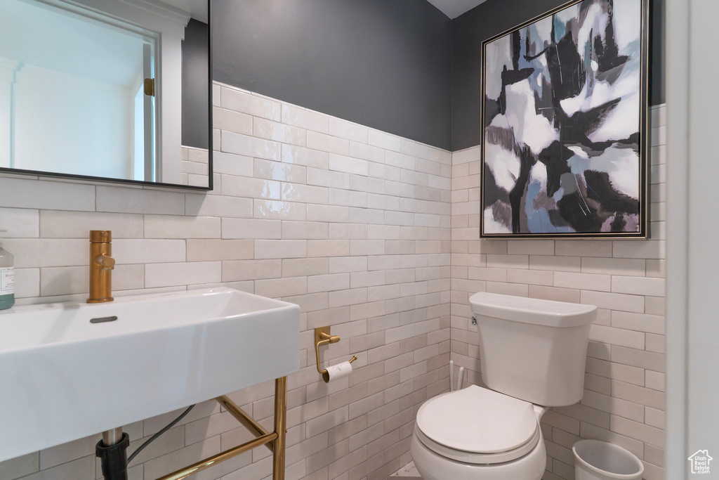 Half bath with tile walls, toilet, and a sink