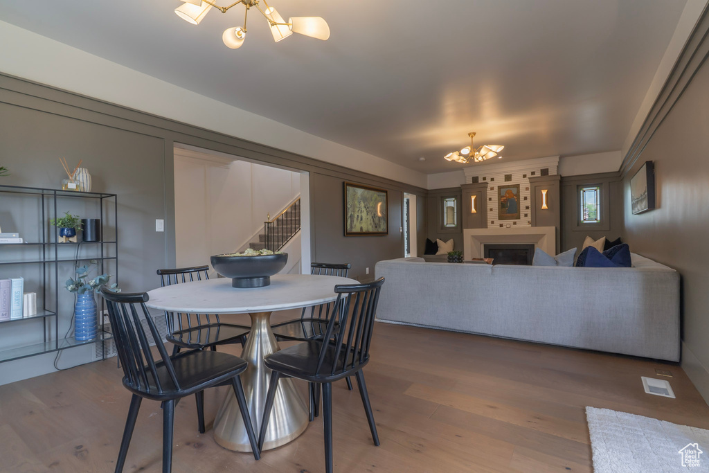 Dining area with a chandelier, stairs, wood finished floors, and a fireplace