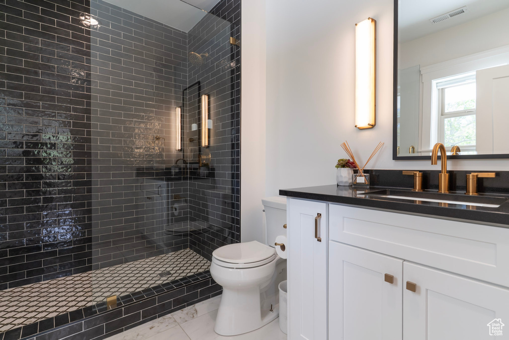 Full bath featuring toilet, vanity, and a tile shower