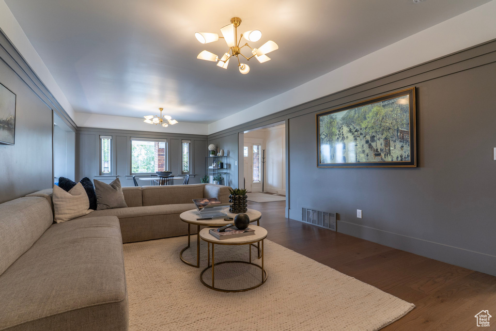 Living area with a chandelier, wood finished floors, and baseboards