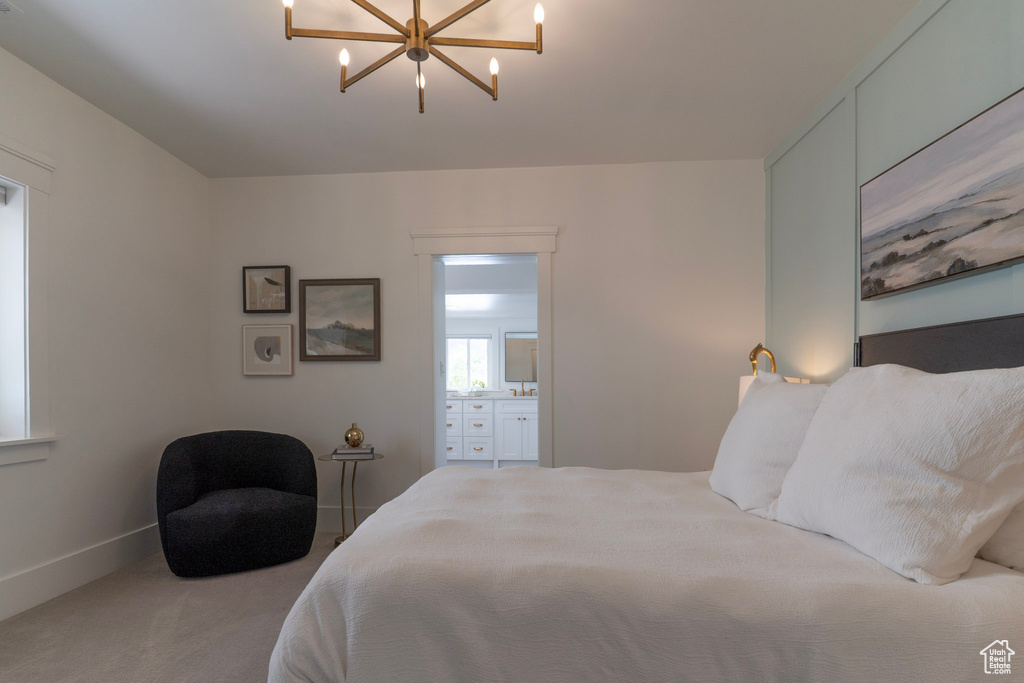 Carpeted bedroom with a chandelier, connected bathroom, and baseboards