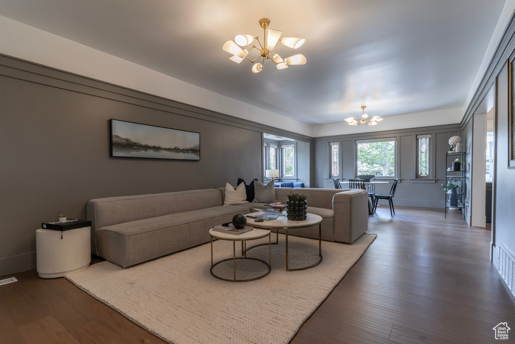 Living area with a chandelier, wood finished floors, and baseboards