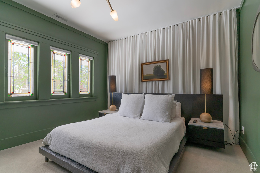 Carpeted bedroom featuring multiple windows and baseboards