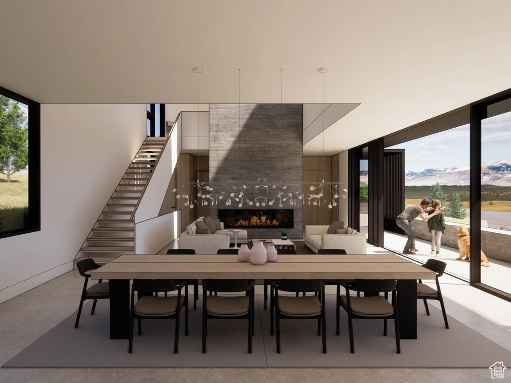 Dining room featuring a tiled fireplace, a mountain view, stairway, concrete floors, and expansive windows