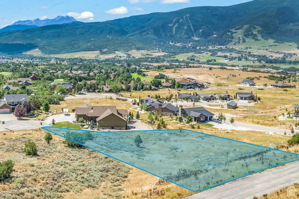 Aerial view of residential area with property parcel outlined and mountains