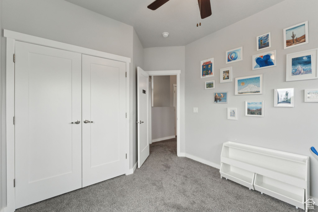 Carpeted bedroom featuring baseboards, ceiling fan, and a closet