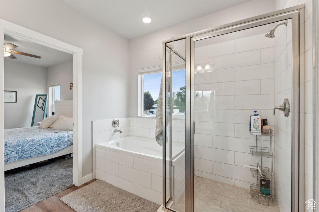 Bathroom featuring ensuite bath, a stall shower, a bath, and wood finished floors