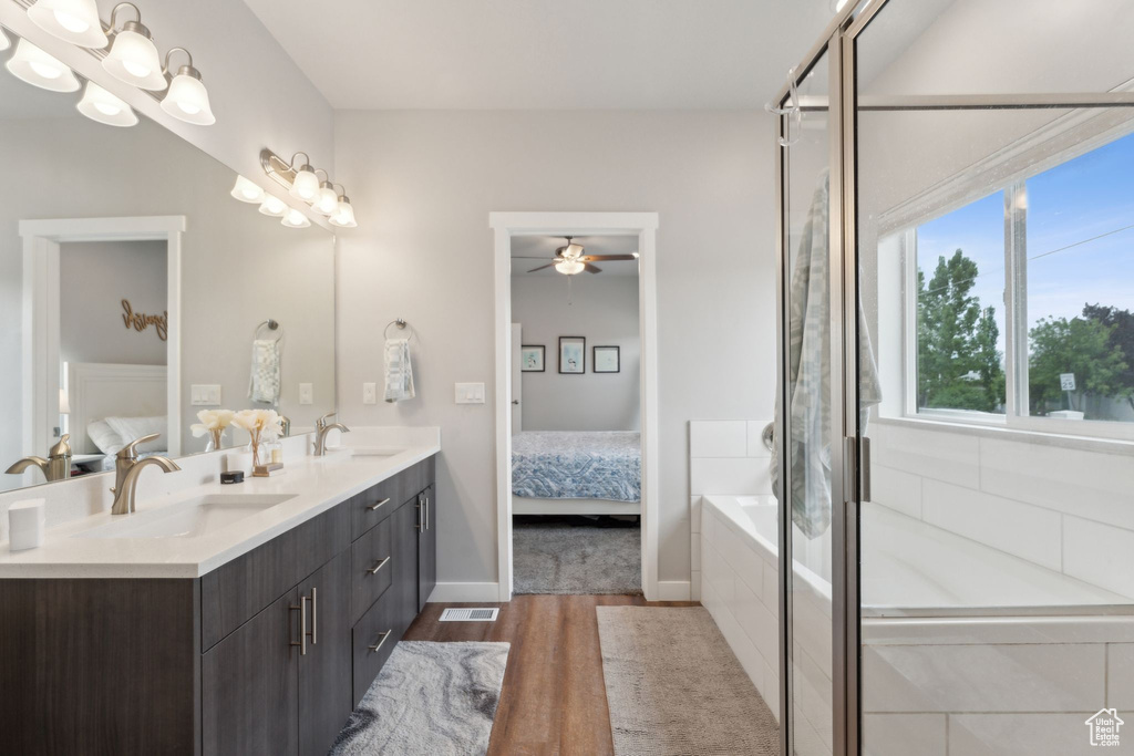 Bathroom with ensuite bath, wood finished floors, ceiling fan, and a tub