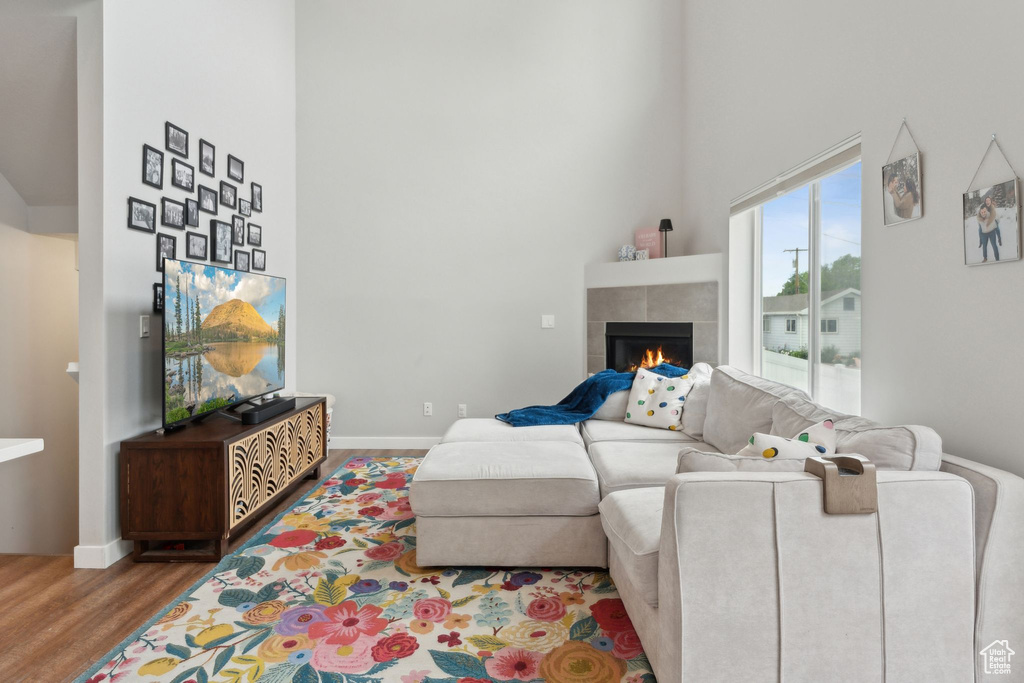 Living area with a high ceiling, wood finished floors, a fireplace, and baseboards