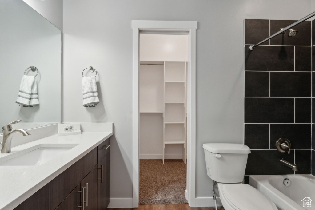 Bathroom featuring bathing tub / shower combination, vanity, toilet, baseboards, and a walk in closet