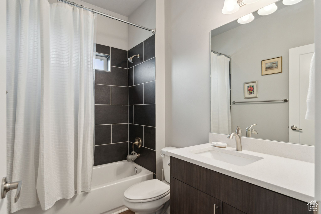 Bathroom with shower / bathtub combination with curtain, toilet, and vanity