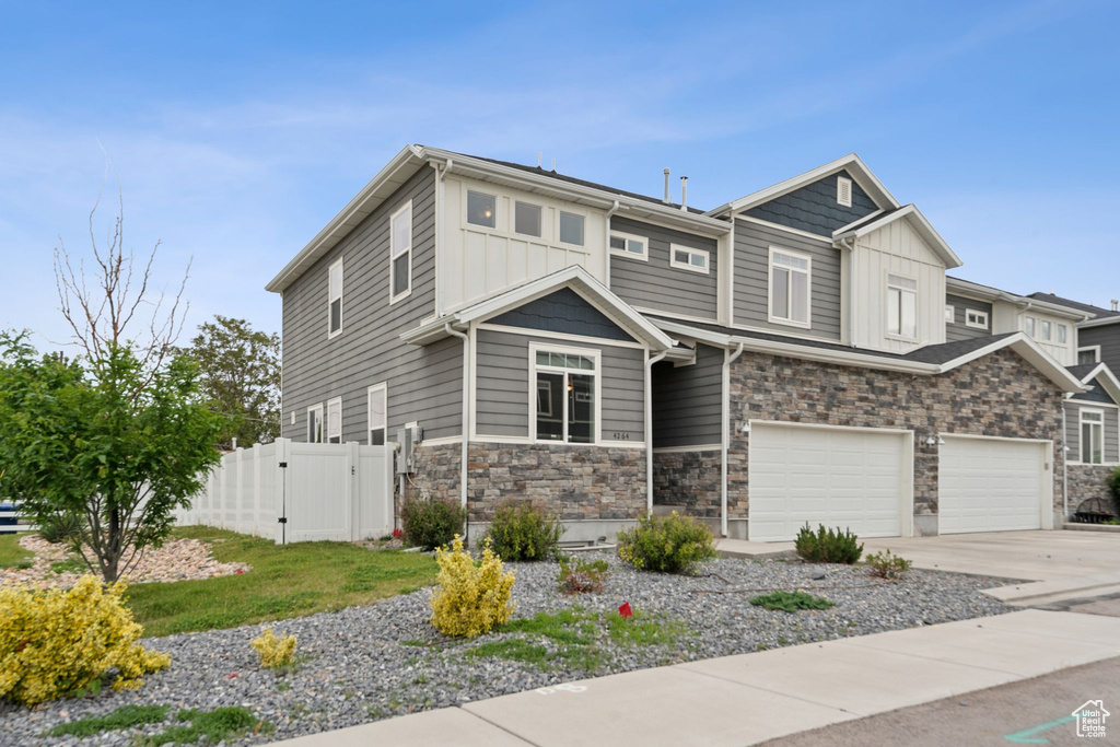 View of front of house featuring fence, a gate, board and batten siding, concrete driveway, and an attached garage