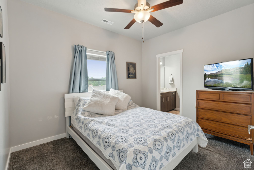 Bedroom with dark carpet, baseboards, a ceiling fan, and ensuite bathroom