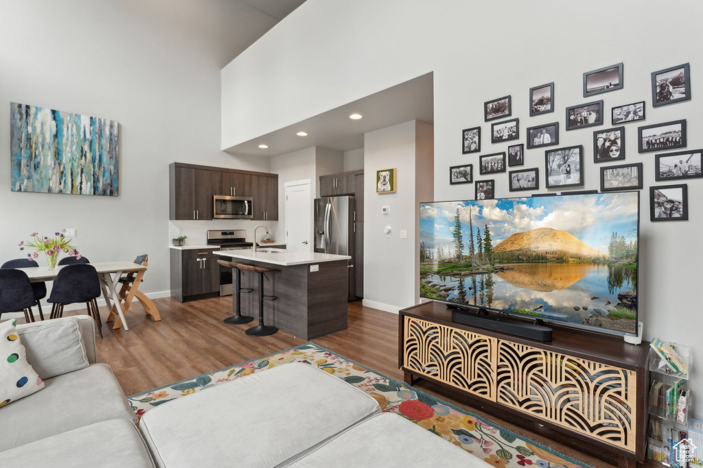 Living area featuring wood finished floors, baseboards, recessed lighting, and a high ceiling