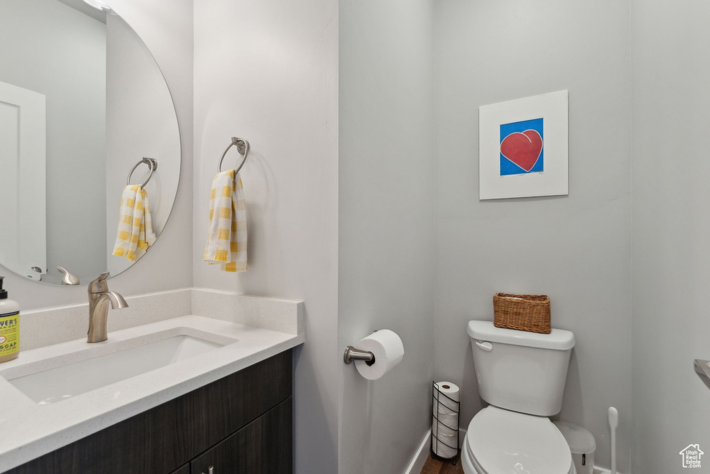 Half bath featuring toilet, vanity, and baseboards