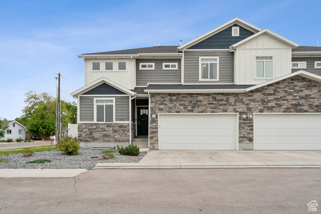 View of front of home featuring stone siding, board and batten siding, an attached garage, and driveway