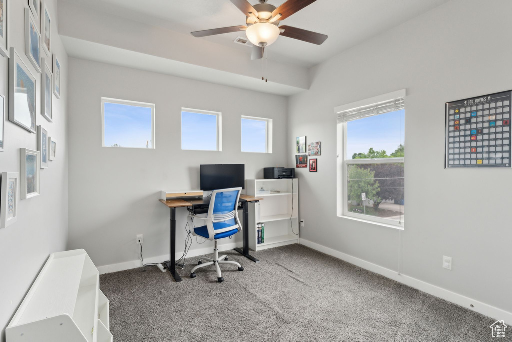 Carpeted office space featuring a ceiling fan and baseboards