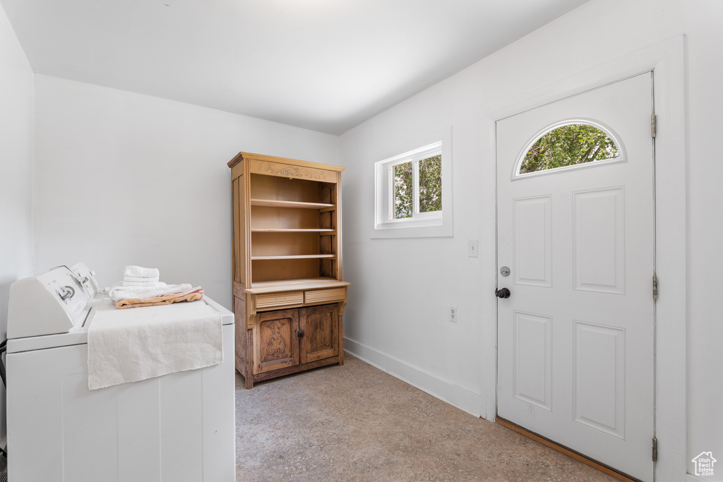 Foyer featuring independent washer and dryer, baseboards, and light carpet