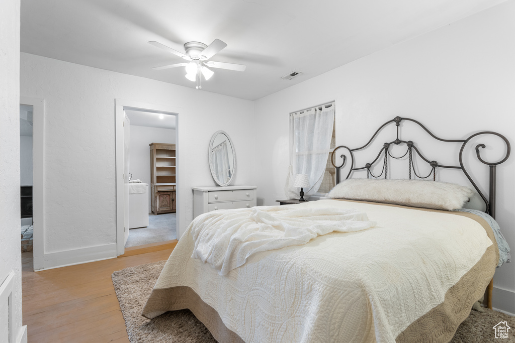 Bedroom with light wood-style floors, a walk in closet, baseboards, and a ceiling fan