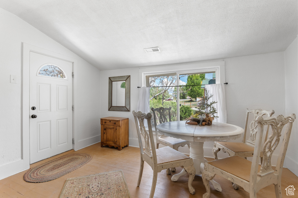 Dining area featuring light wood-style flooring, vaulted ceiling, and baseboards